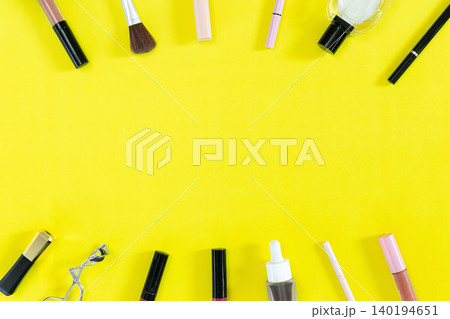 Bright yellow backdrop frames colorful cosmetics. Brushes, lipsticks, and tubes rest neatly arranged. Top and bottom borders hold beauty tools in order. Minimalist style draws attention to each item Bright yellow backdrop frames colorful cosmetics. Brushes, lipsticks, and tubes rest neatly arranged. Top and bottom borders hold beauty tools in order. Minimalist style draws attention to each item 140194651