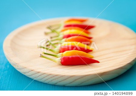 colorful hot chili peppers in a row on plate colorful hot chili peppers in a row on plate 140194899