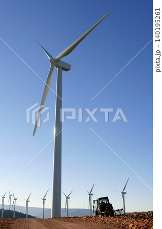 Agriculture tractor under electric wind mills in blue sky Agriculture tractor under electric wind mills in blue sky 140195261