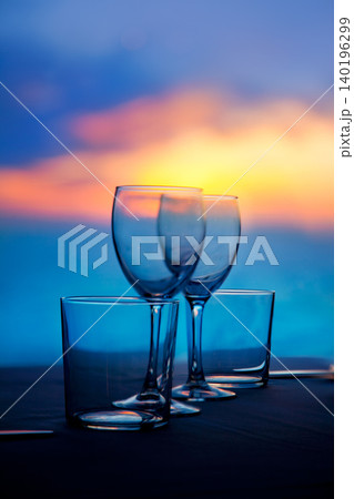 Dish of cups and crystal glasses on sea sunset Dish of cups and crystal glasses on sea sunset 140196299