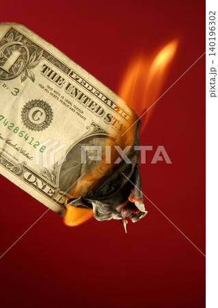 Dollar note burning in fire over red 140196302