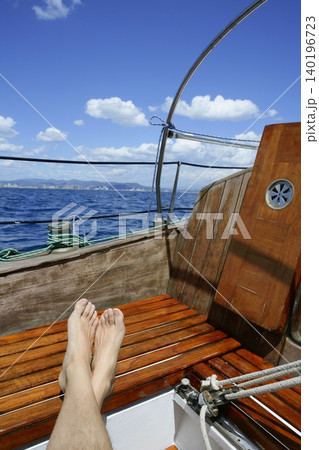 man feet relax on golden wooden old sailboat man feet relax on golden wooden old sailboat 140196723