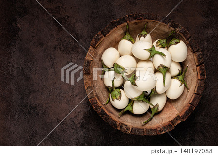 white mini eggplant, in a wooden bowl, on the table, close-up. white mini eggplant, in a wooden bowl, on the table, close-up. 140197088