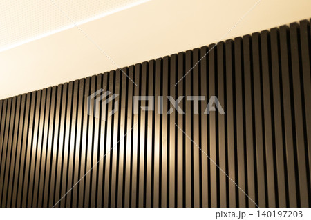 Dark vertical slats on curved wall with illuminated ceiling in modern interior Dark vertical slats on curved wall with illuminated ceiling in modern interior 140197203