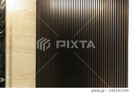 Dark vertical wooden slats wall texture with beige travertine stone panel 140197204