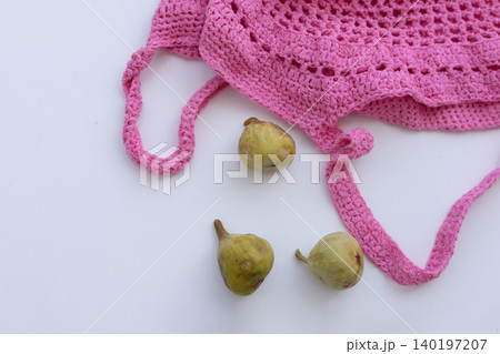 Green Figs with Pink Knitted Mesh Bag on White Background Green Figs with Pink Knitted Mesh Bag on White Background 140197207