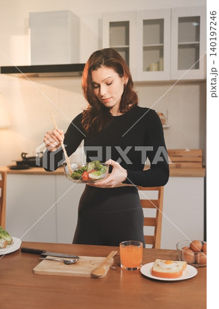 Woman preparing green smoothie in bright kitchen with fresh fruits and vegetables, healthy eating lifestyle moment in natural daylight Woman preparing green smoothie in bright kitchen with fresh fruits and vegetables, healthy eating lifestyle moment in natural daylight 140197246