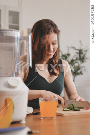 Woman preparing green smoothie in bright kitchen with fresh fruits and vegetables, healthy eating lifestyle moment in natural daylight Woman preparing green smoothie in bright kitchen with fresh fruits and vegetables, healthy eating lifestyle moment in natural daylight 140197262