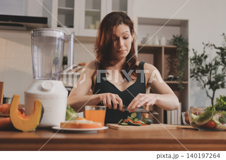Woman preparing green smoothie in bright kitchen with fresh fruits and vegetables, healthy eating lifestyle moment in natural daylight Woman preparing green smoothie in bright kitchen with fresh fruits and vegetables, healthy eating lifestyle moment in natural daylight 140197264
