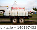 A white mobile drinking water station tank trailer parked at an outdoor festival field with white event tents 140197432