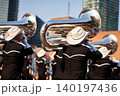 Marching band takes part in the Calgary Stampede Parade. Musicians play instruments while wearing bright outfits. People watch from the sidelines in a lively crowd 140197436
