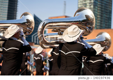 Marching band takes part in the Calgary Stampede Parade. Musicians play instruments while wearing bright outfits. People watch from the sidelines in a lively crowd Marching band takes part in the Calgary Stampede Parade. Musicians play instruments while wearing bright outfits. People watch from the sidelines in a lively crowd 140197436