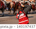 A media photographer in a red press vest taking pictures of a horse procession during the Calgary Stampede Parade. 140197437