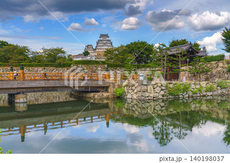 Himeji, Japan - Sep 24 2024, panoramic view of pond, bridge in front of fortress wall with gates of Himeji Castle, White Heron Castle, with castle itself in background, at daytime, Himeji, Japan 140198037