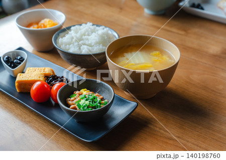 木製のテーブルに並ぶご飯と味噌汁、納豆などの一汁三菜の和朝食 木製のテーブルに並ぶご飯と味噌汁、納豆などの一汁三菜の和朝食 140198760