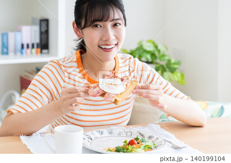 リビングで朝食を食べる若い女性 リビングで朝食を食べる若い女性 140199104