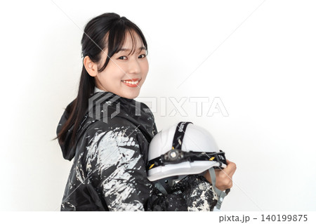 ペンキ汚れの作業着を着てヘルメットを持つ笑顔の若い女性作業員 白背景 140199875