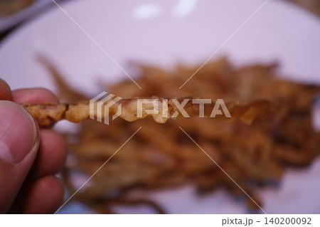 Hand Holding Crispy Fried Snack Close-Up 140200092
