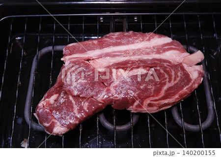 Raw Ribeye Steaks on Grill Rack Raw Ribeye Steaks on Grill Rack 140200155