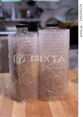 Bottles in Bubble Wrap on Wooden Surface Bottles in Bubble Wrap on Wooden Surface 140200254