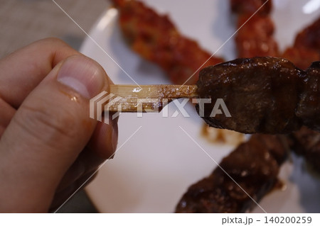 Grilled Meat Skewer Held by Hand Close-Up 140200259