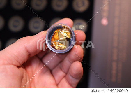 Hand Holding Small Container with Gold Foil Object Hand Holding Small Container with Gold Foil Object 140200640