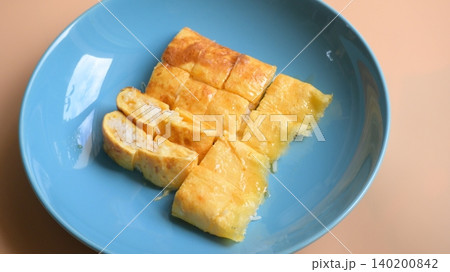 roll omelette stuffed with chesse and rice on blue plate, delicious food in the morning roll omelette stuffed with chesse and rice on blue plate, delicious food in the morning 140200842