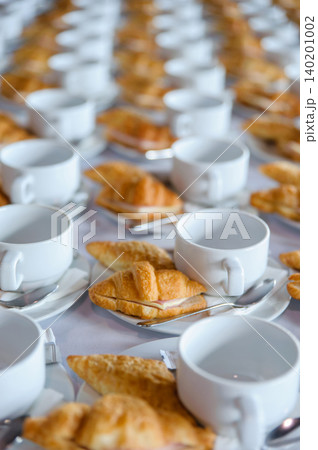 many line of croissant on a dish with empty coffee cups many line of croissant on a dish with empty coffee cups 140201002