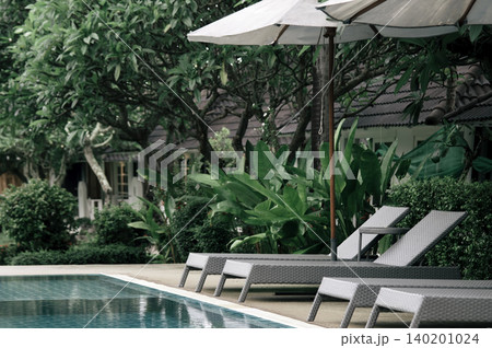 beach mattress at pool side with white umbella and garden nearby in the resort somewhere in Thailand beach mattress at pool side with white umbella and garden nearby in the resort somewhere in Thailand 140201024