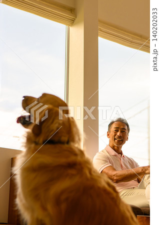 窓辺で犬と過ごす男性 140202033