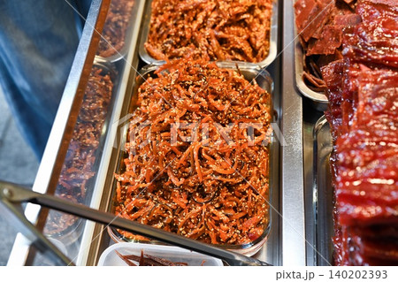 Traditional Chinese shredded sweet pork jerky meat floss with sesame seeds inside glass tray at street food bakery shop display counter in Macau Traditional Chinese shredded sweet pork jerky meat floss with sesame seeds inside glass tray at street food bakery shop display counter in Macau 140202393