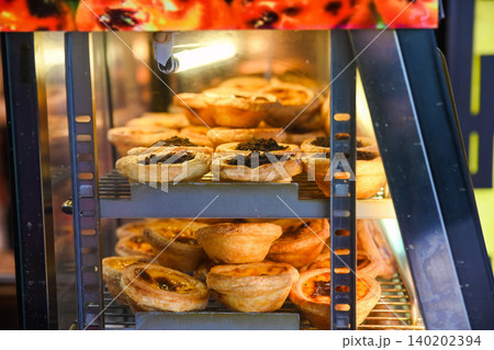 Traditional Macanese Portuguese egg tarts pastel de nata and chocolate topping tarts inside heated display showcase at local bakery shop in Macau Traditional Macanese Portuguese egg tarts pastel de nata and chocolate topping tarts inside heated display showcase at local bakery shop in Macau 140202394