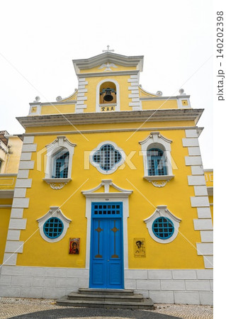 Beautiful yellow facade of historic Chapel of St Francis Xavier built in 1928 with blue wooden door at Eduardo Marques square in Coloane Macau China Beautiful yellow facade of historic Chapel of St Francis Xavier built in 1928 with blue wooden door at Eduardo Marques square in Coloane Macau China 140202398