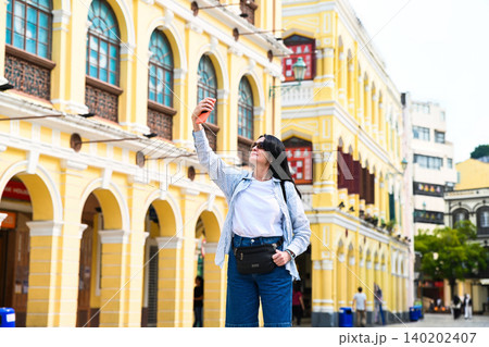 Mature 50 years old Russian woman tourist taking selfie on street at historic unesco senado square during travel vacation in Macau China Mature 50 years old Russian woman tourist taking selfie on street at historic unesco senado square during travel vacation in Macau China 140202407