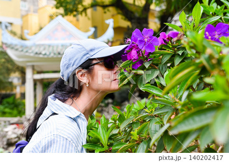 Profile of mature 50 years old Russian woman tourist brunet smelling purple princess flower at Lou Lim Ioc Garden during vacation in Macau China Profile of mature 50 years old Russian woman tourist brunet smelling purple princess flower at Lou Lim Ioc Garden during vacation in Macau China 140202417