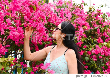 Happy 50 years old Russian woman tourist enjoying solo travel near pink bougainvillea flowers in beautiful Coloane Macau China Happy 50 years old Russian woman tourist enjoying solo travel near pink bougainvillea flowers in beautiful Coloane Macau China 140202429