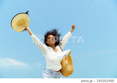Happy young black woman stretching arms on sunny beach Happy young black woman stretching arms on sunny beach 140202480
