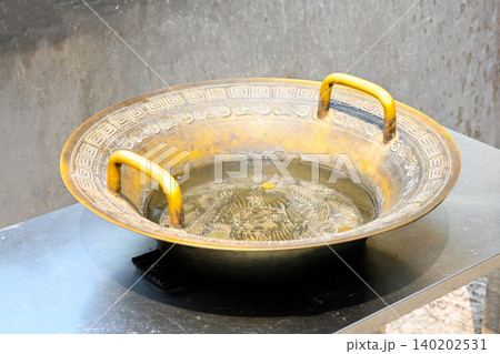 Ancient traditional bronze dragon water basin filled with coins at famous historical A-Ma Temple religious landmark in Macau travel destination China 140202531