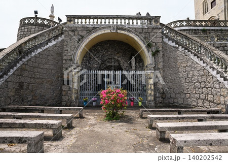Ancient stone grotto of Our Lady of Lourdes with statues and benches at historical Penha Chapel landmark in Macau travel destination China Ancient stone grotto of Our Lady of Lourdes with statues and benches at historical Penha Chapel landmark in Macau travel destination China 140202542