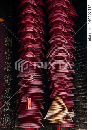 Traditional spiral incense coils hanging with ancient Chinese couplet on pillar meaning eternal paying of respects inside historical Pak Tai Temple Traditional spiral incense coils hanging with ancient Chinese couplet on pillar meaning eternal paying of respects inside historical Pak Tai Temple 140202556