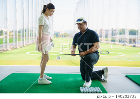 Professional golf coach adjusting posture for female student Professional golf coach adjusting posture for female student 140202735