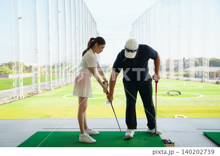 Professional golf coach adjusting posture for female student 140202739