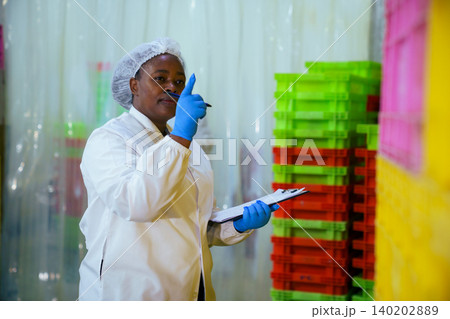 Female factory worker with clipboard checking stock in food plant Female factory worker with clipboard checking stock in food plant 140202889