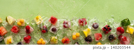 Green background with ice cubes with frozen berries and fruits and mint, banner Green background with ice cubes with frozen berries and fruits and mint, banner 140203544