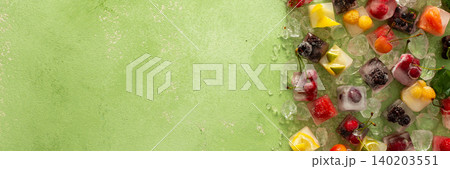 Green background with ice cubes with frozen berries and fruits and mint, banner Green background with ice cubes with frozen berries and fruits and mint, banner 140203551