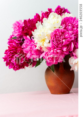A vibrant arrangement of pink and white peonies showcases their lush petals. This floral display brings energy and beauty to any celebration or home decor setting 140203558