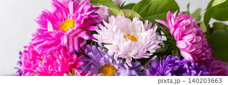 A group of flowers in shades of pink, purple, and white are gathered in a vase. The vase rests on a table. The setting is bright and shows the flowers clearly, banner A group of flowers in shades of pink, purple, and white are gathered in a vase. The vase rests on a table. The setting is bright and shows the flowers clearly, banner 140203663