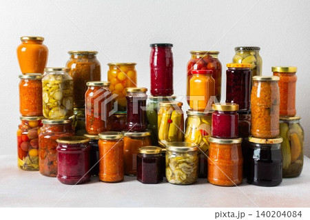 Canned vegetables and fruits are stacked on a shelf, prepared for winter use. Various jars hold different preserves, showcasing careful efforts for storing food during the season Canned vegetables and fruits are stacked on a shelf, prepared for winter use. Various jars hold different preserves, showcasing careful efforts for storing food during the season 140204084