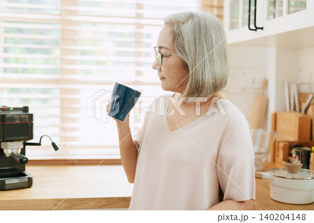 Senior Asian woman standing hand holding coffee cup, Elder drinks tea or coffee in the morning. Senior Asian woman standing hand holding coffee cup, Elder drinks tea or coffee in the morning. 140204148