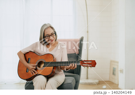 Healthy Senior Asian woman musician playing guitar music lover at living room indoors home. Healthy Senior Asian woman musician playing guitar music lover at living room indoors home. 140204149